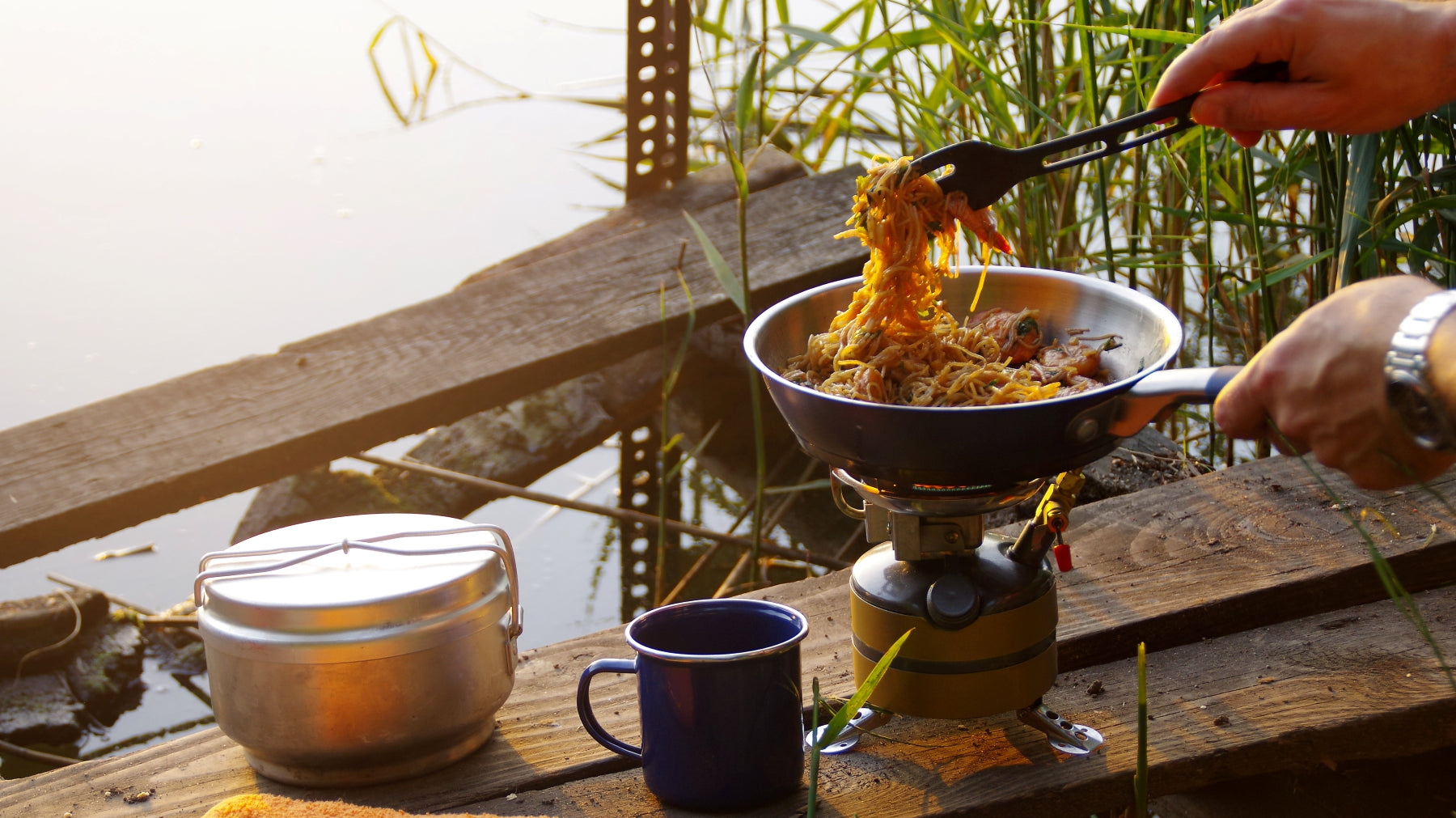 man cooking while camping outside in the woods