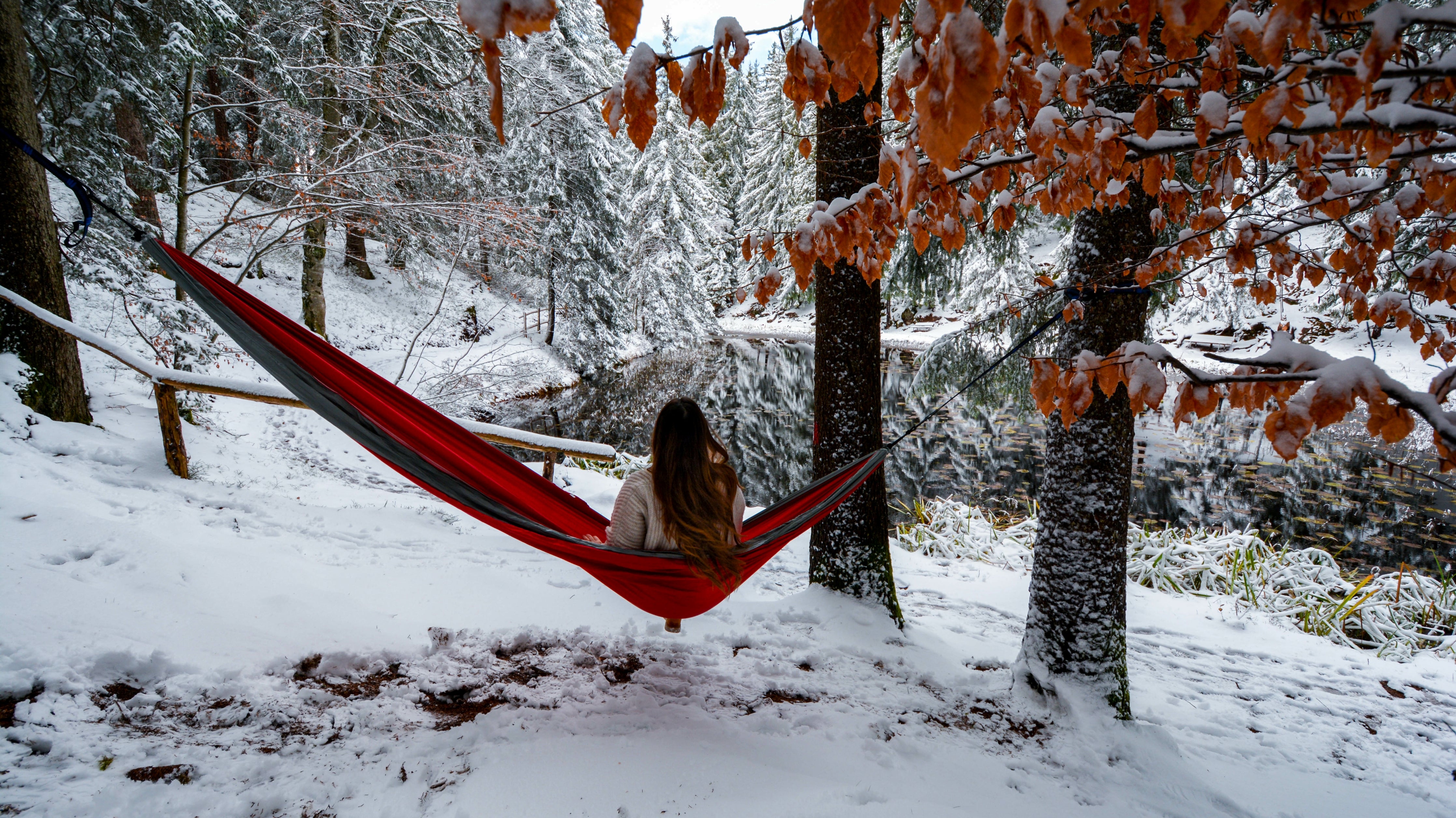 women sitting in camping hammock during winter looking at snowy landscape