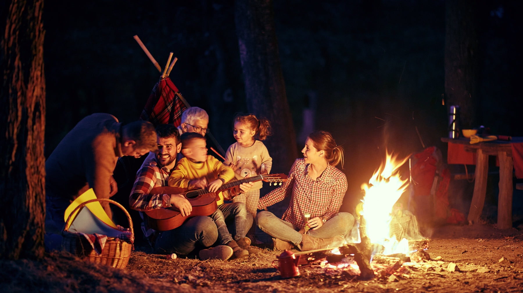 family enjoying some outdoor night activities for kids by a campfire roasting marshmallows