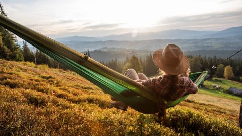 person-relaxing-in-a-hammock-looking-at-the-mountains