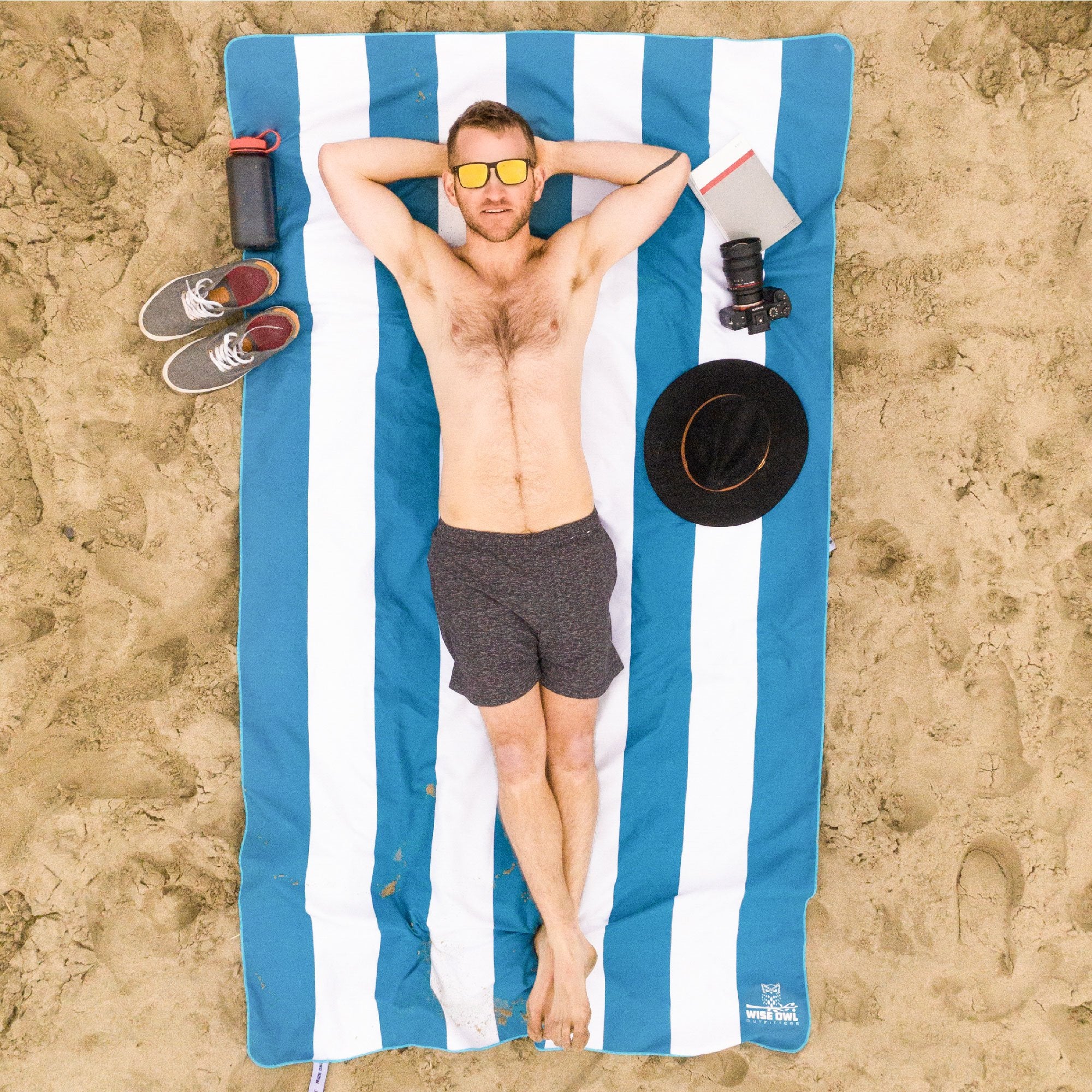 Man laying on a Blue Striped Beach Towel