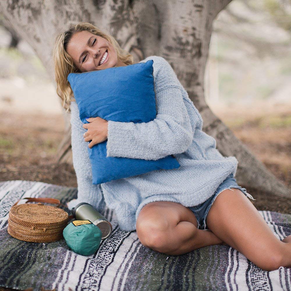 Women hugging camping pillow outside in the woods.