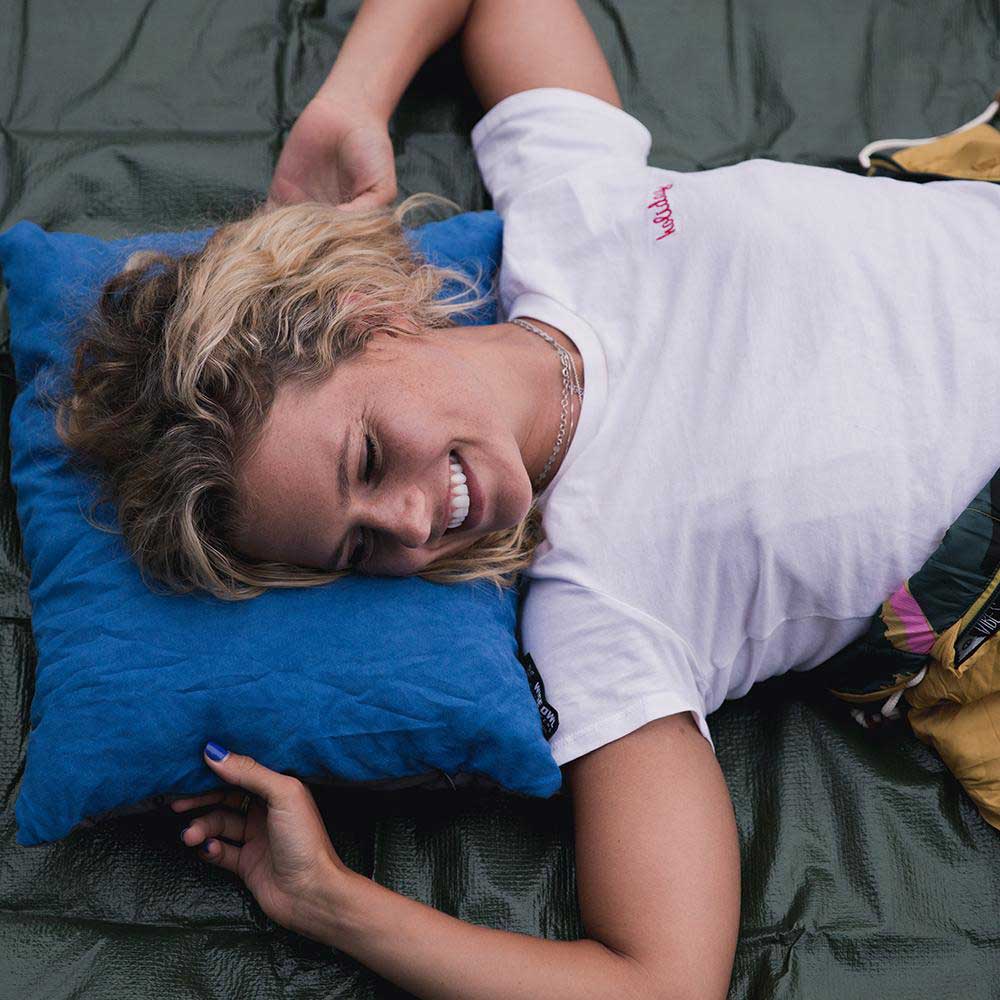 Women laying on a camping pillow outdoors while camping.