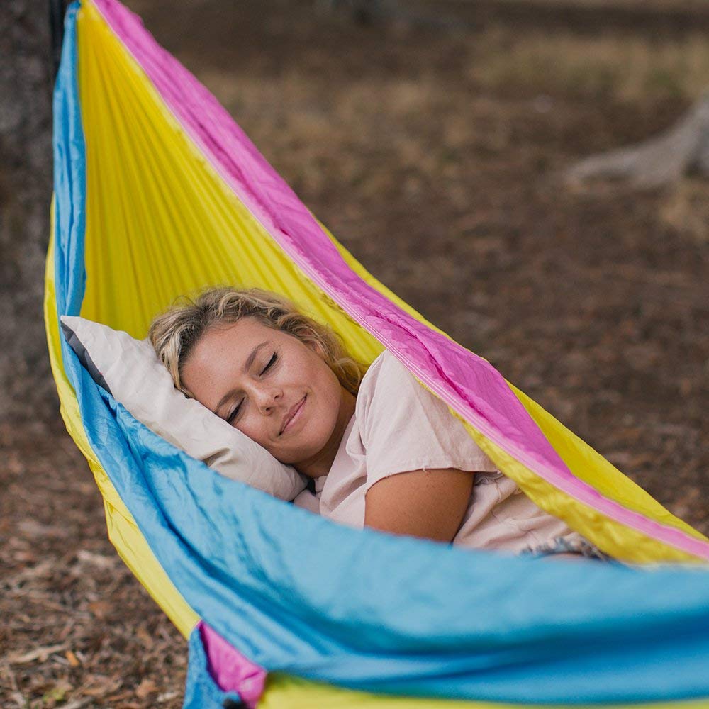 Women sleeping on a camping pillow outside in a hammock while camping.