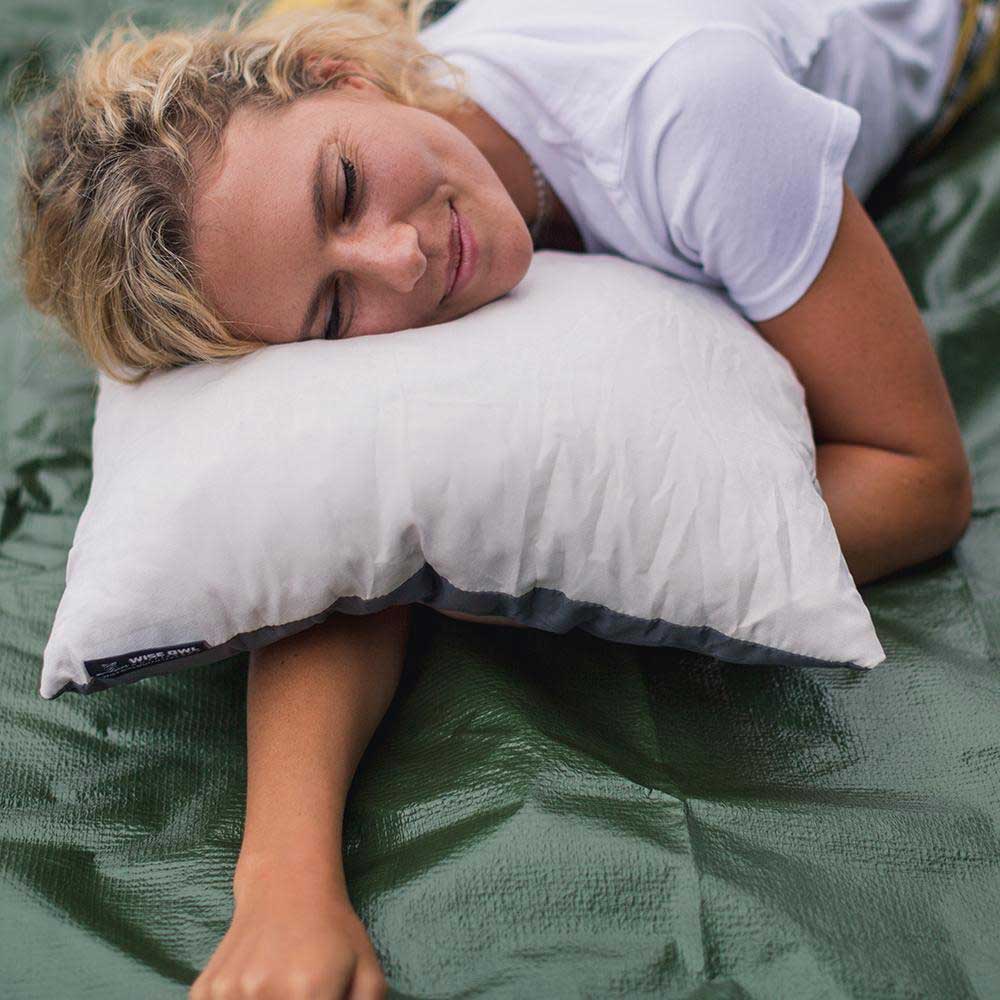 Women laying on a camping pillow outside in the woods.