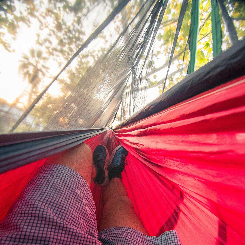 Man in a hammock using a hammock bug net.