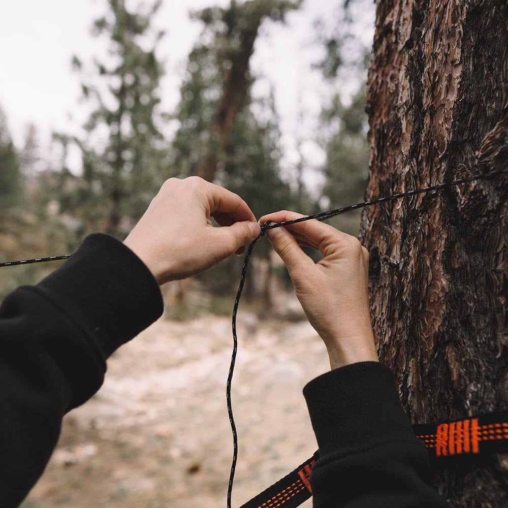 Man tying rope to set up a hammock bug net.