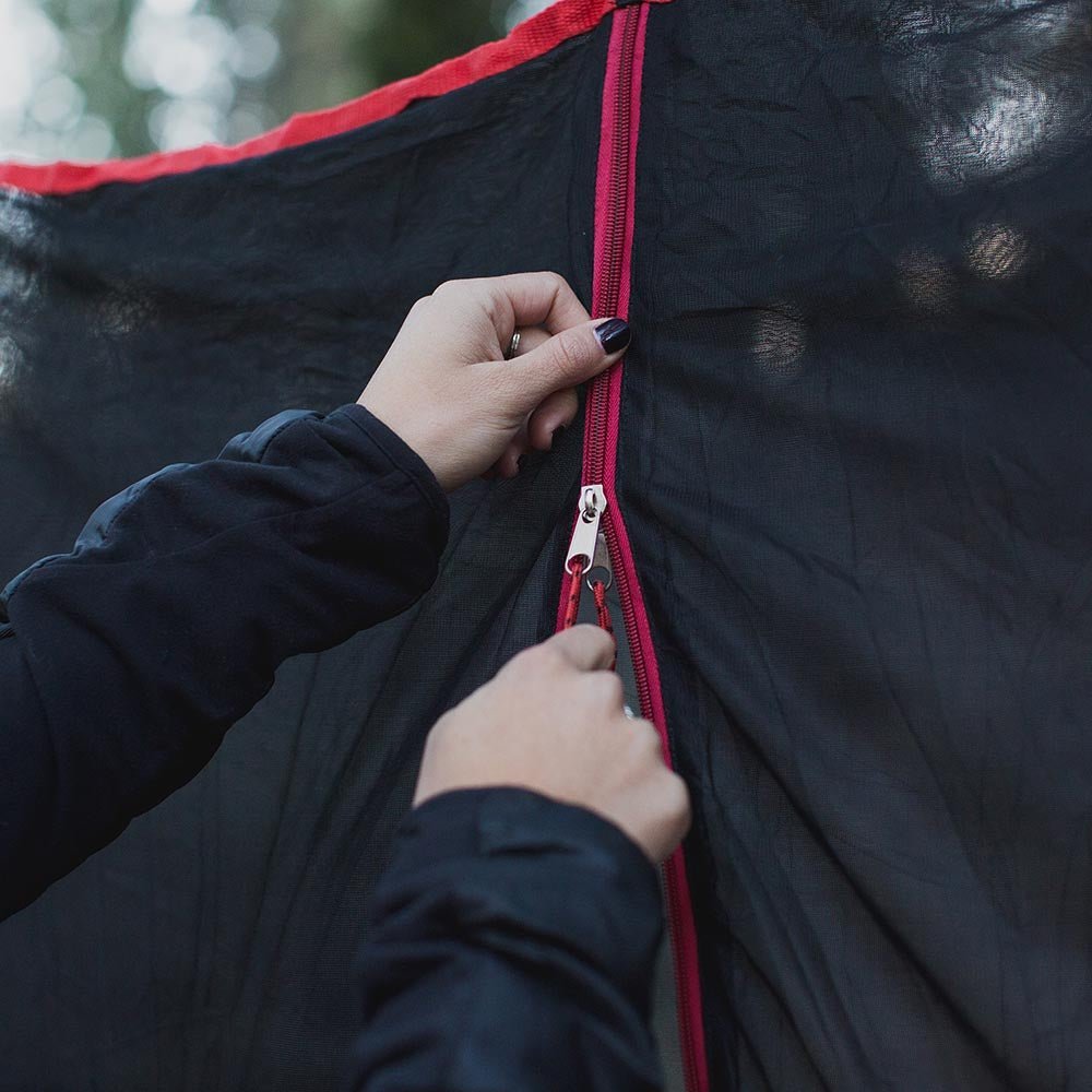 Women using a hammock bug net zipper to keep bugs away.