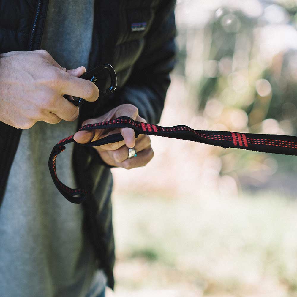 Man using hooks to securely put up hammock straps around a tree.