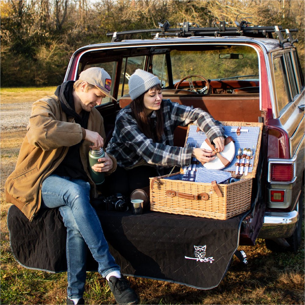 Couple enjoying a picnic outside using an outdoor blanket.