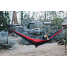 Women smiling outdoors in the woods in a portable hammock.