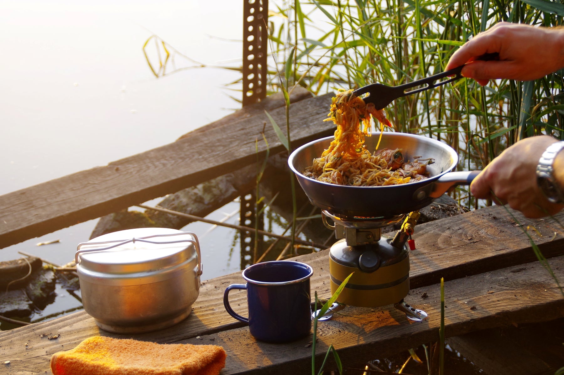 man cooking while camping outside in the woods