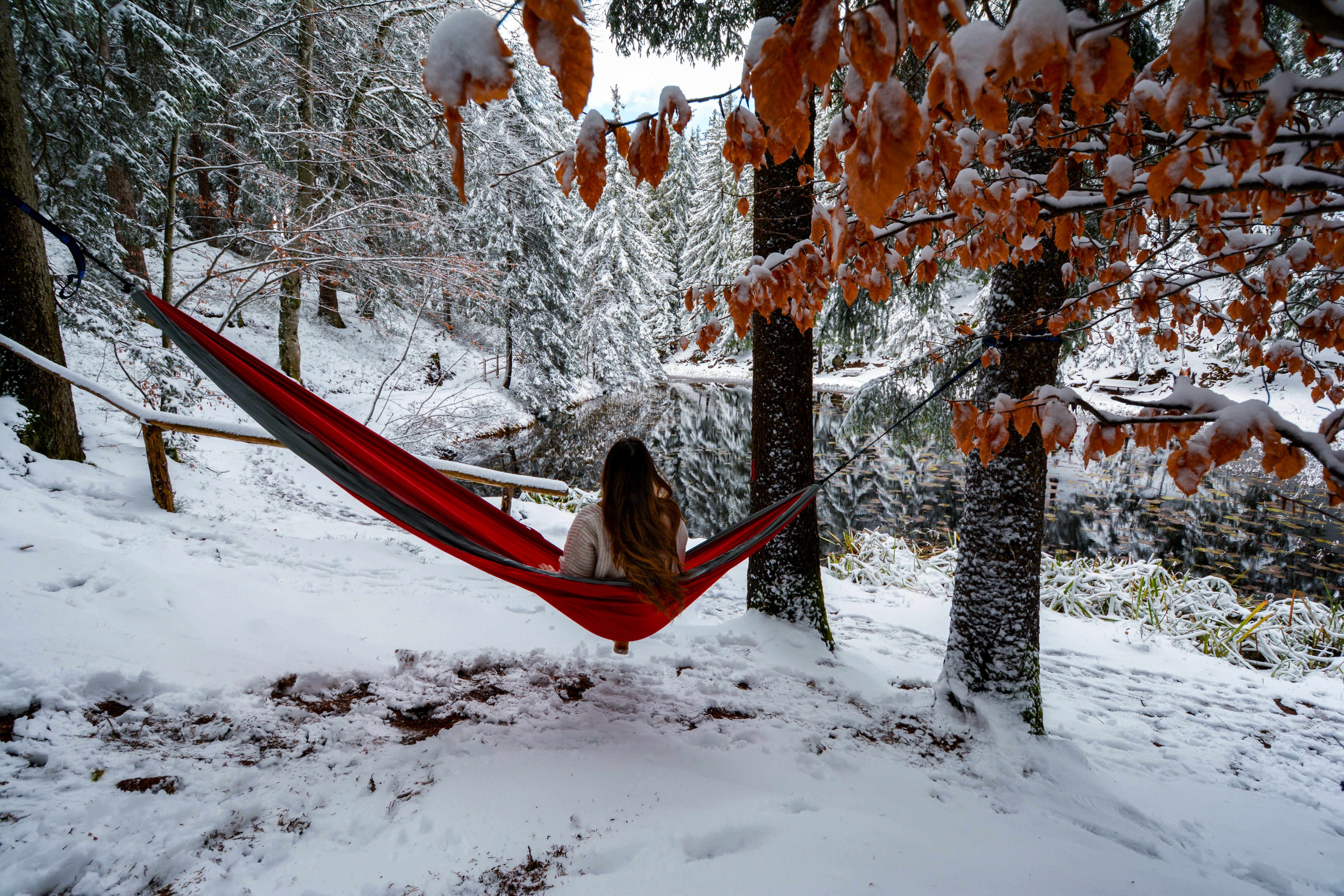 women sitting in camping hammock during winter looking at snowy landscape