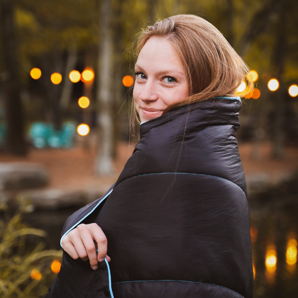 Women using a camping blanket to stay warm outdoors.
