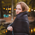 Women using a camping blanket to stay warm outdoors.