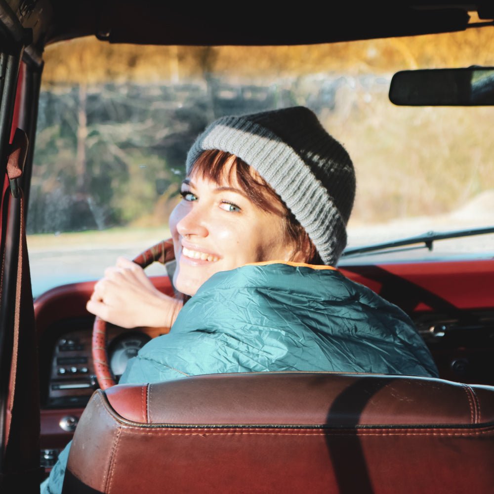 Women using a camping blanket in the car to warm up.