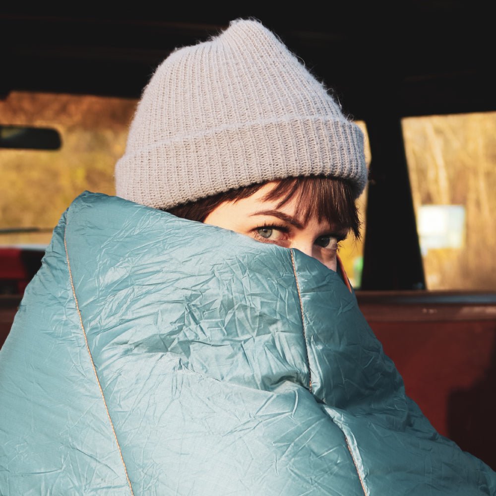Women using a camping blanket to stay warm while on an outdoor trip.