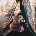 Women using a camera in a hammock with a hammock bug net.