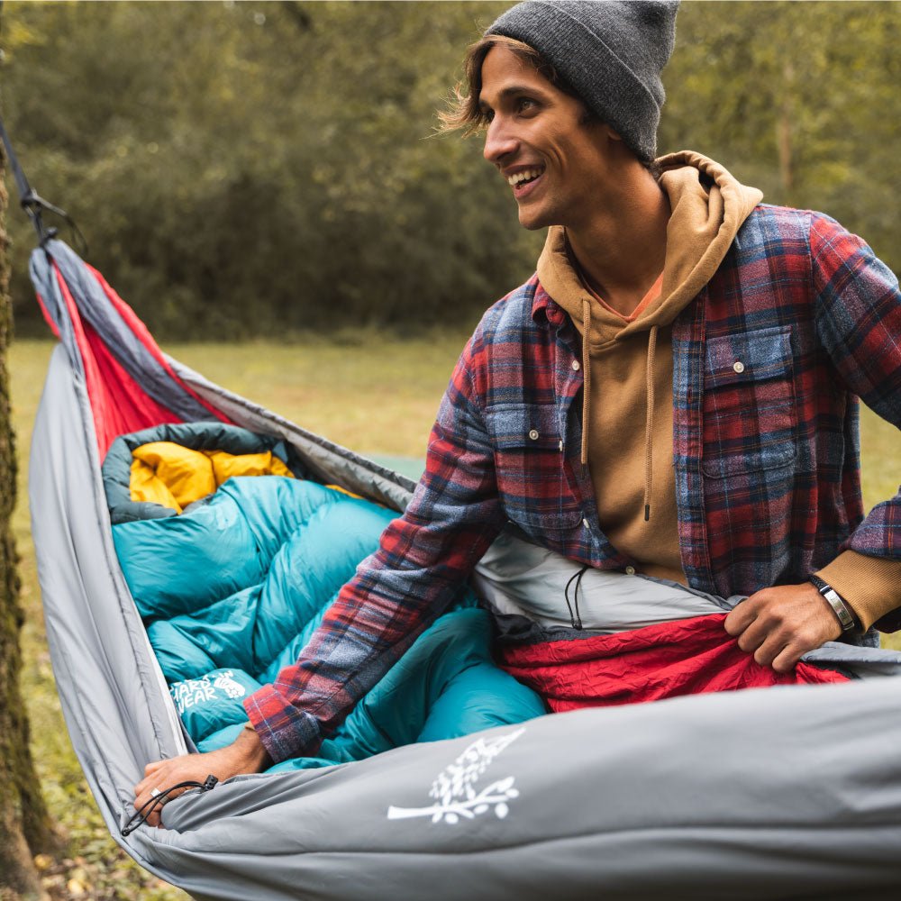 Man opening a hammock underquilt because it is cold outside.