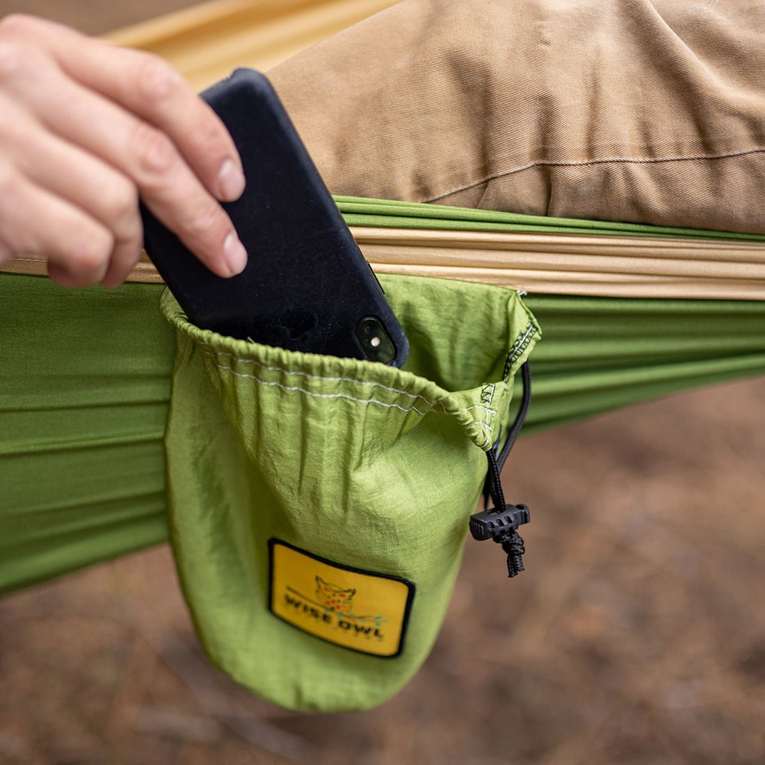 Man putting phone in phone pocket in the camping hammock. 