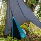 Man in a hammock underneath a waterproof hammock tarp used to stay dry.
